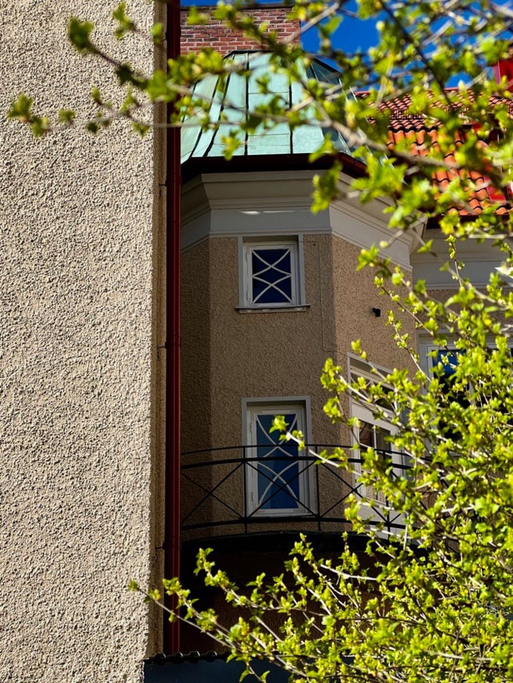 Bygning innrammet av husvegg og greiner