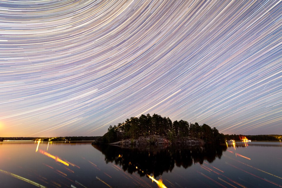 Startrails over en innsjø med en øy. Foto: Mikael Järnåsen.